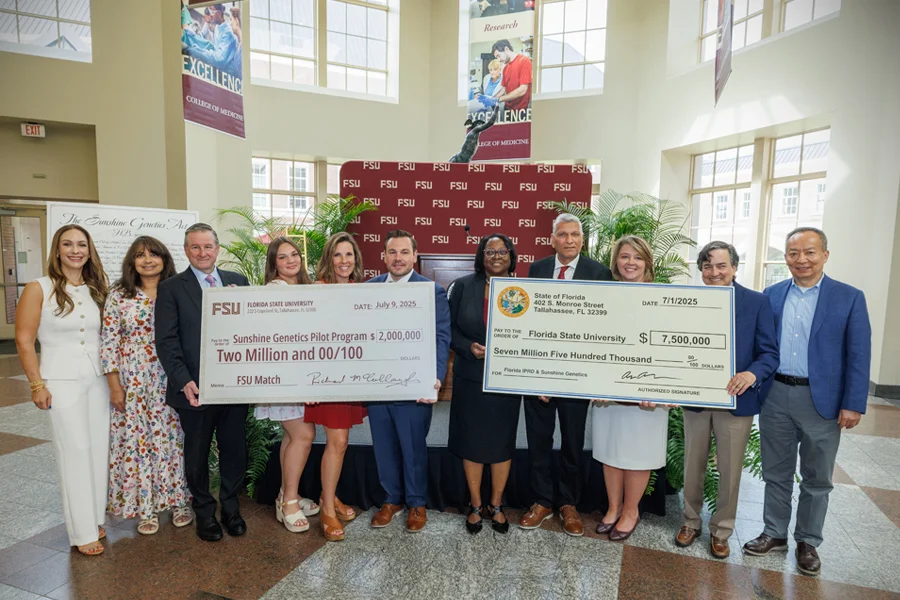 Group of people holding large checks for the Sunshine Genetics Act
